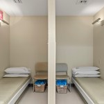 Two private treatment or post-op recovery bays separated by a partition; each contains a cushioned bed, pillow, and storage basket — designed for patient comfort and privacy